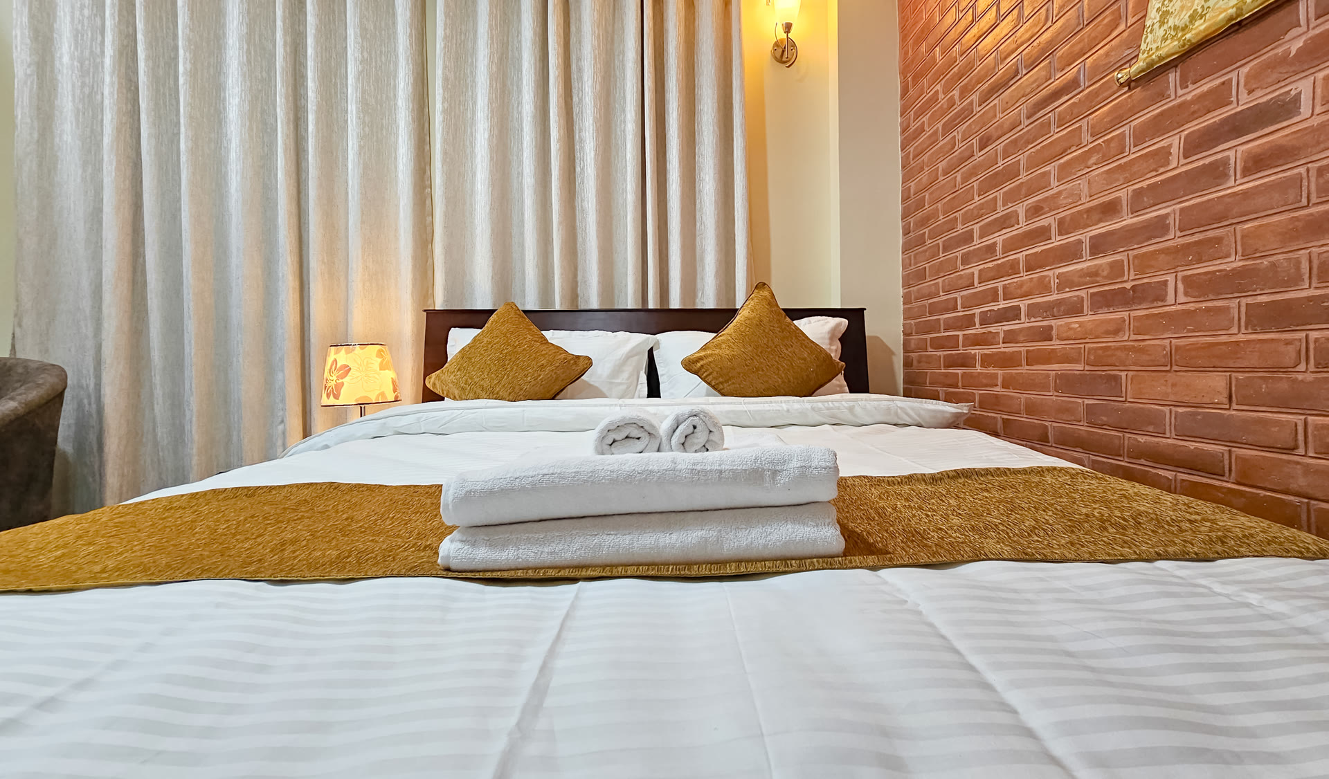 Queen bedroom with Newari brick wall at Badri Homes